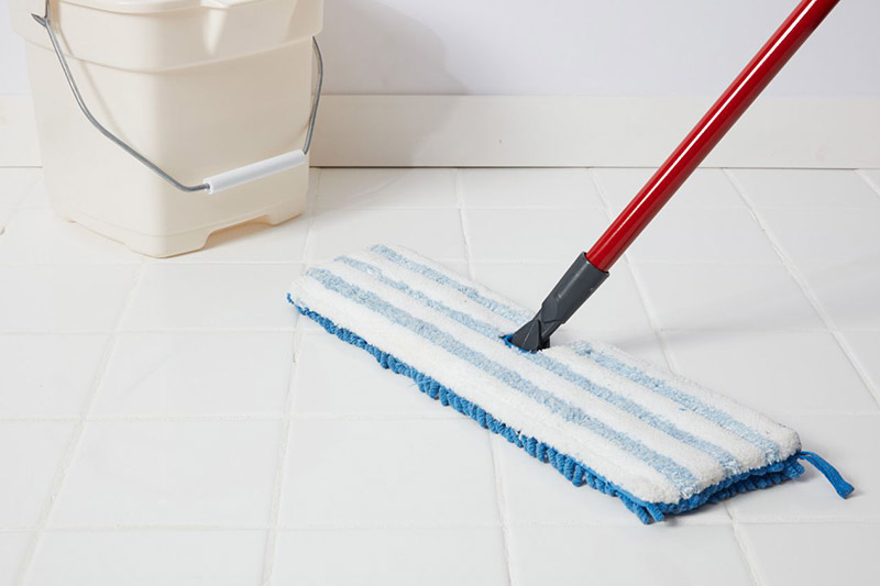 یک تی مسطح در کنار سطل برای تمیز کردن سرامیک کف