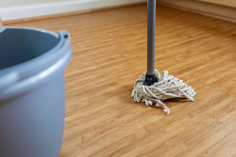 یک تی نخی در کنار سطل برای نظافت کفپوش پارکت